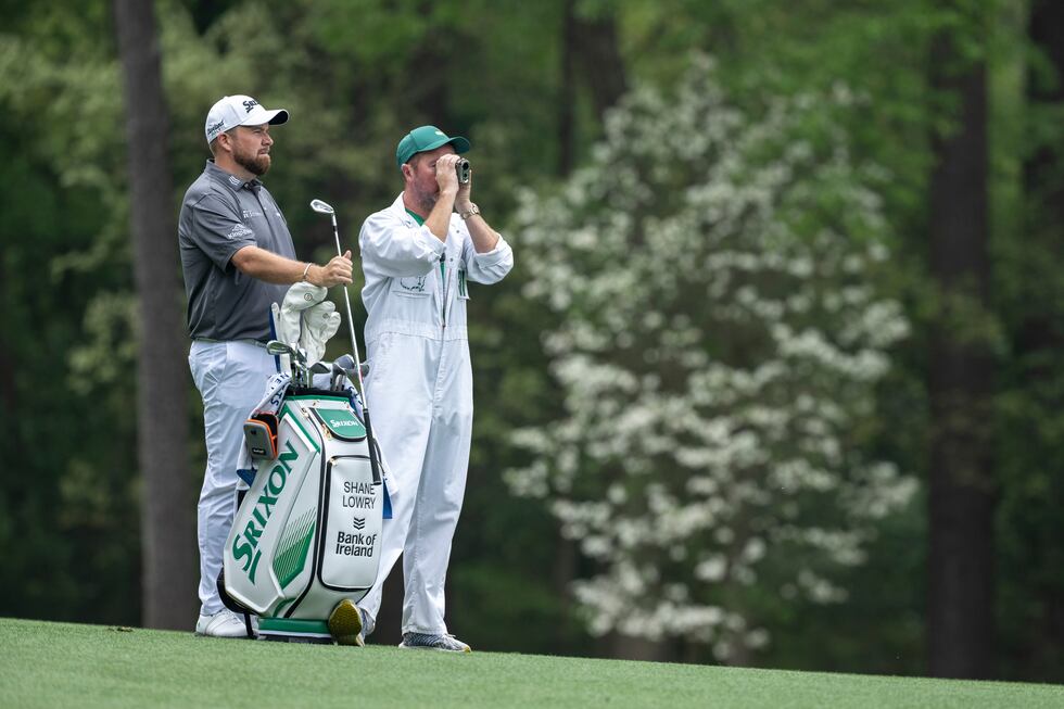 Shane Lowry of Ireland and his caddie Darren Reynolds use a rangefinder to look down the No....